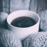 Grey mittened hands holding hot drink